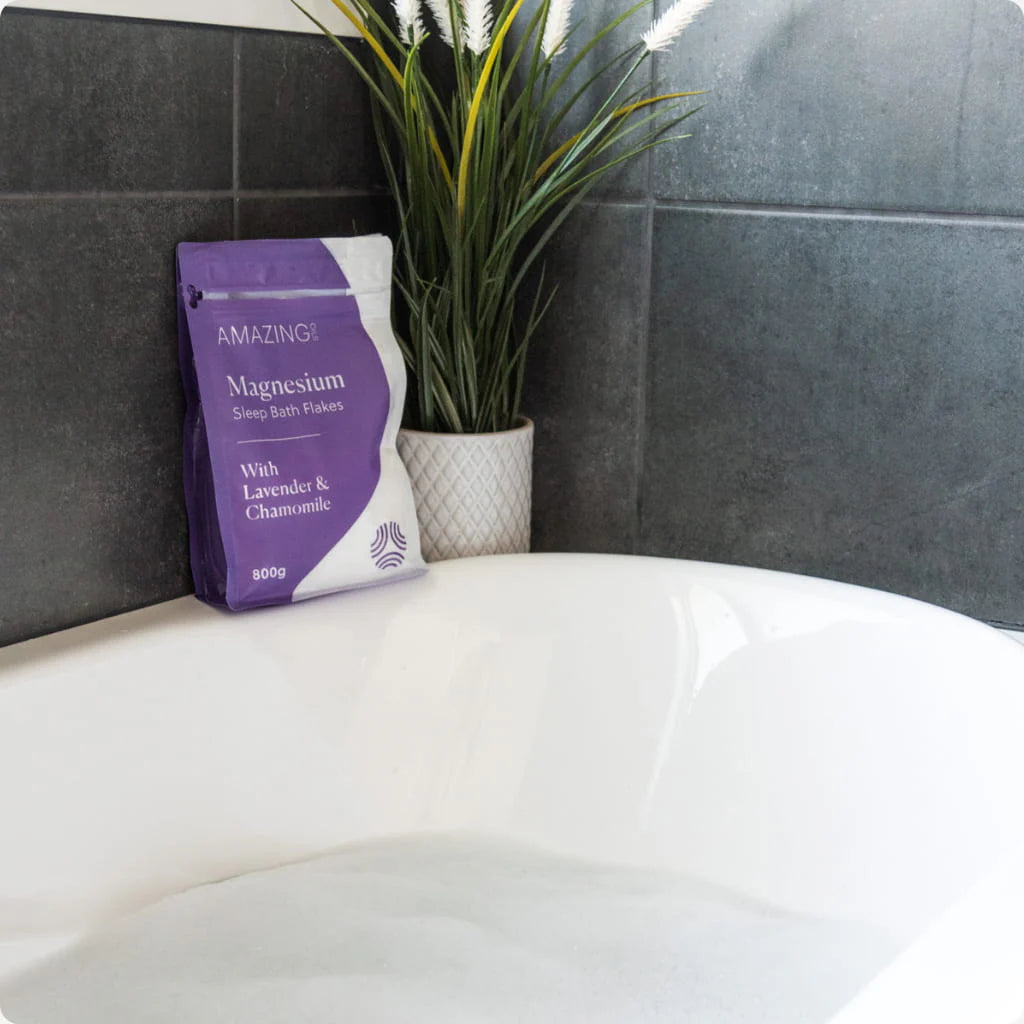 Bag of magnesium bath flakes on a white surface with a plant in the background. Magnesium bath flakes for sleep—relax muscles, ease stress, and support deep sleep through a calming evening soak. Amazing Oils Australian stockist. Geelong based. Shop now!